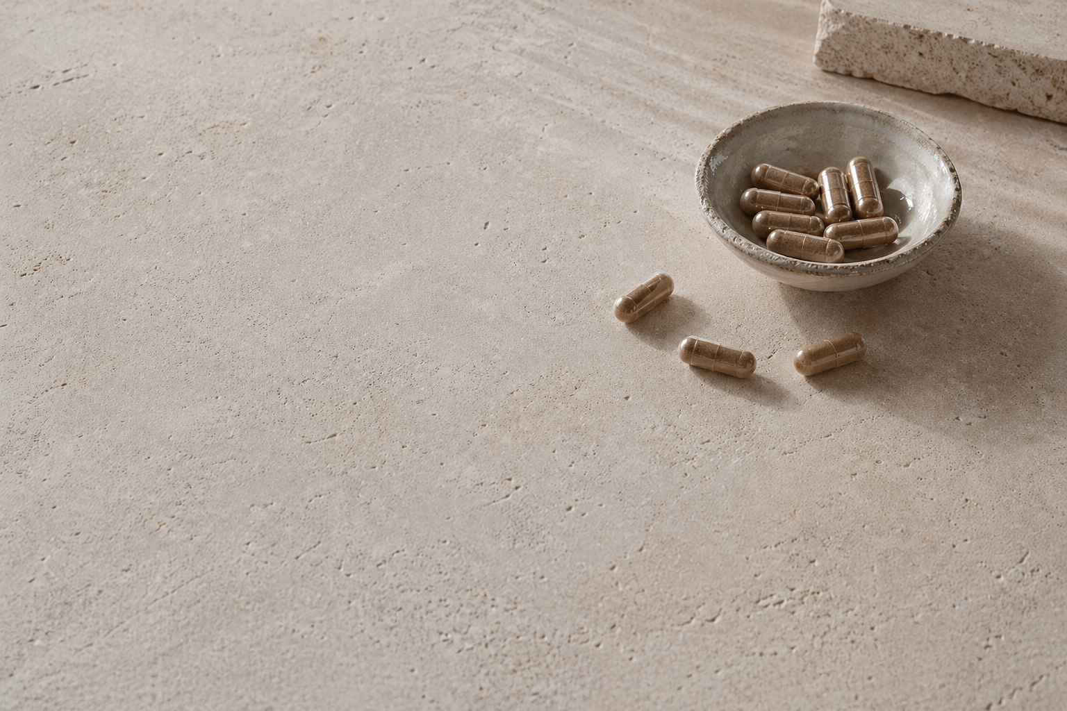 Brown organ powder capsules in ceramic bowl on natural stone