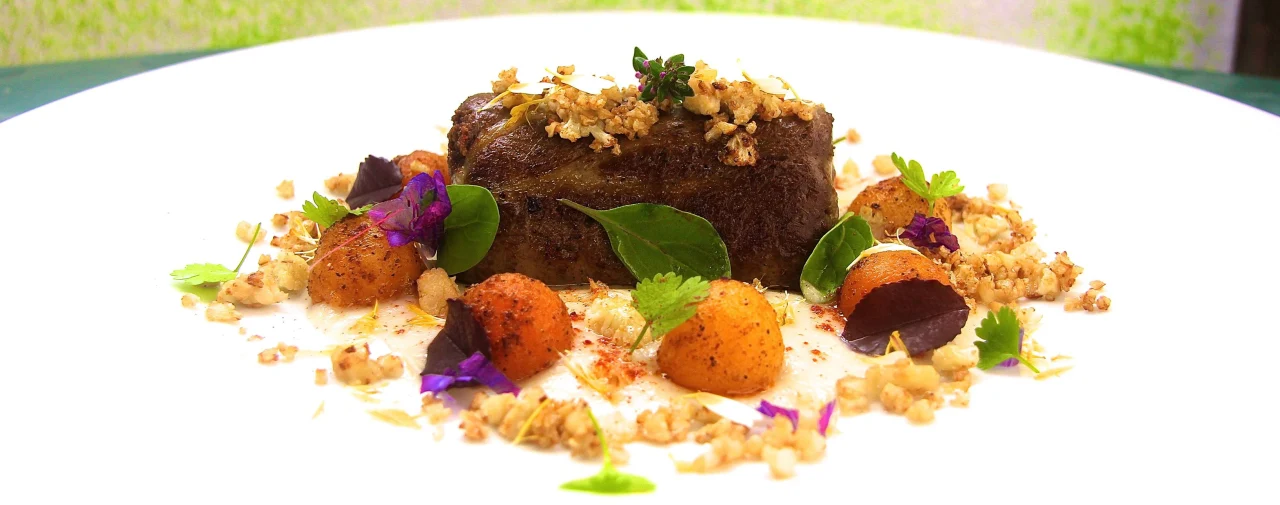 Um prato contemporâneo português de fígado com legumes e ervas num prato branco